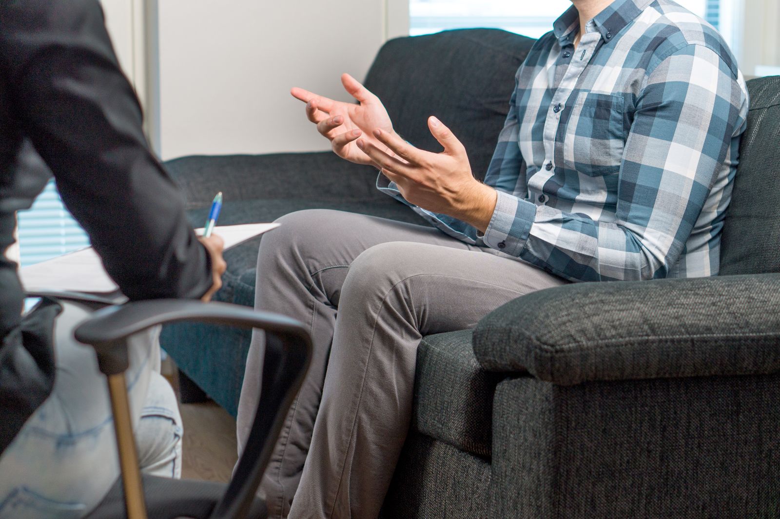 A patient sitting on a couch speaking with a provider. 