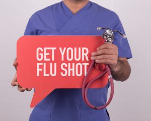 A physician holding a flu shot sign
