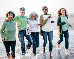 A smiling group of women running on the beach