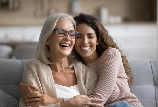 A woman hugging her mother on a couch