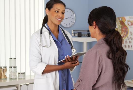 A smiling physician with a seated patient