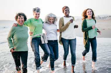 A smiling group of women running on the beach