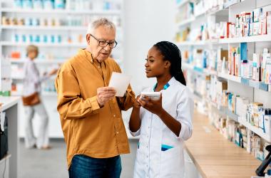 A man showing a prescription slip to a pharmacy