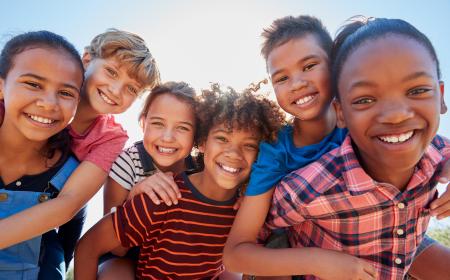 A smiling group of children outside