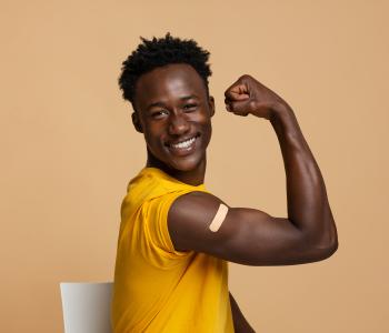 A smiling man flexing his arm after a flu shot