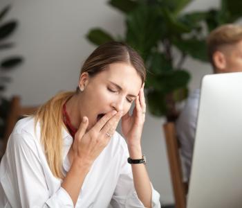 A woman at her computer yawning