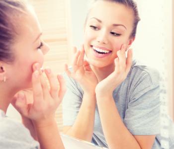 A teen looking at her face in the mirror