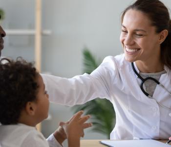 Friendly female doctor examining a child sitting sit on dads lap