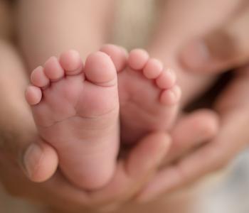 A mother holding a newborn babies feet