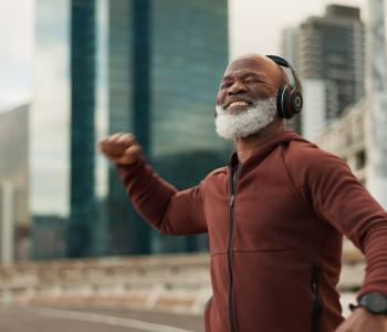 A smiling man dancing outside to music in his headphones