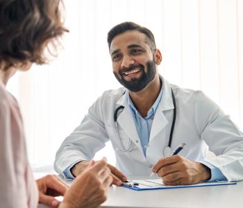 A patient sitting across a table from their smiling physician